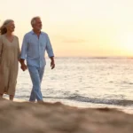 A happy retired couple walking on a beach at sunset, symbolizing a fulfilling retirement.