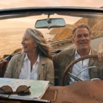 A mature couple enjoys a scenic coastal road trip at sunset, symbolizing the freedom and adventure of retirement travel.