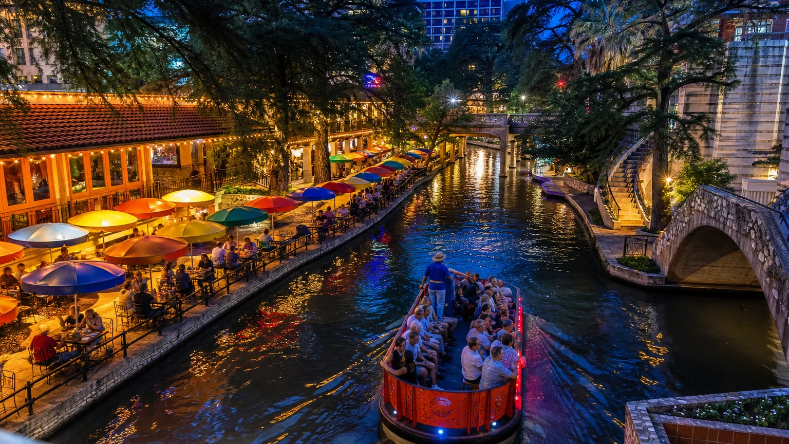 A tour boat carries passengers along the San Antonio River Walk at twilight, surrounded by lit cafes and cypress trees.