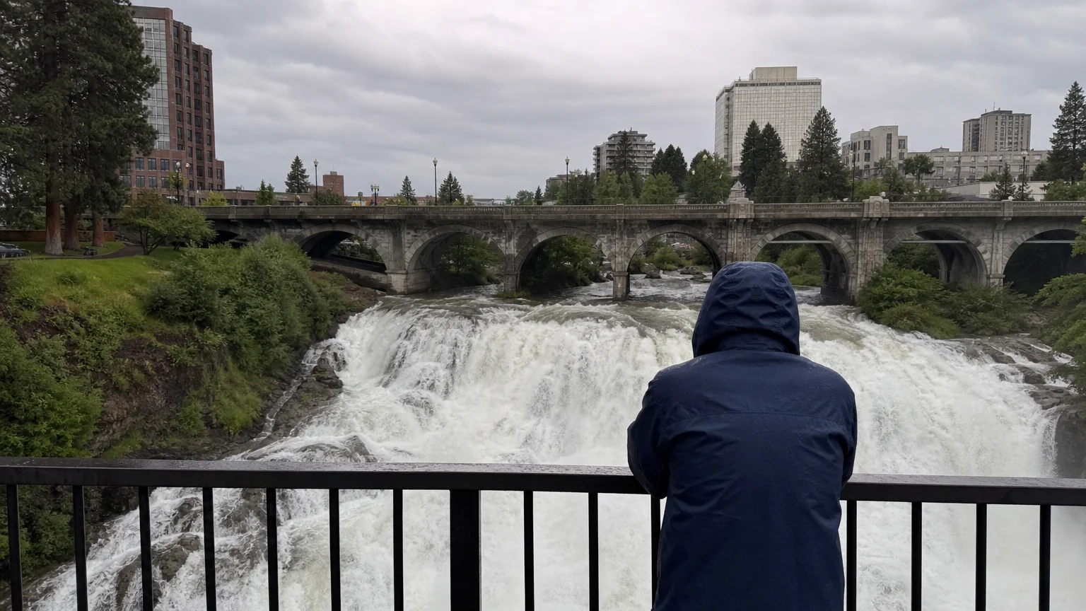 A wide-angle photo of Spokane Falls with a historic bridge in the background on a cool, cloudy day.
